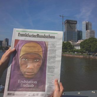 Foto: Eine Person hält eine Ausgabe der Frankfurter Rundschau in die Kamera
