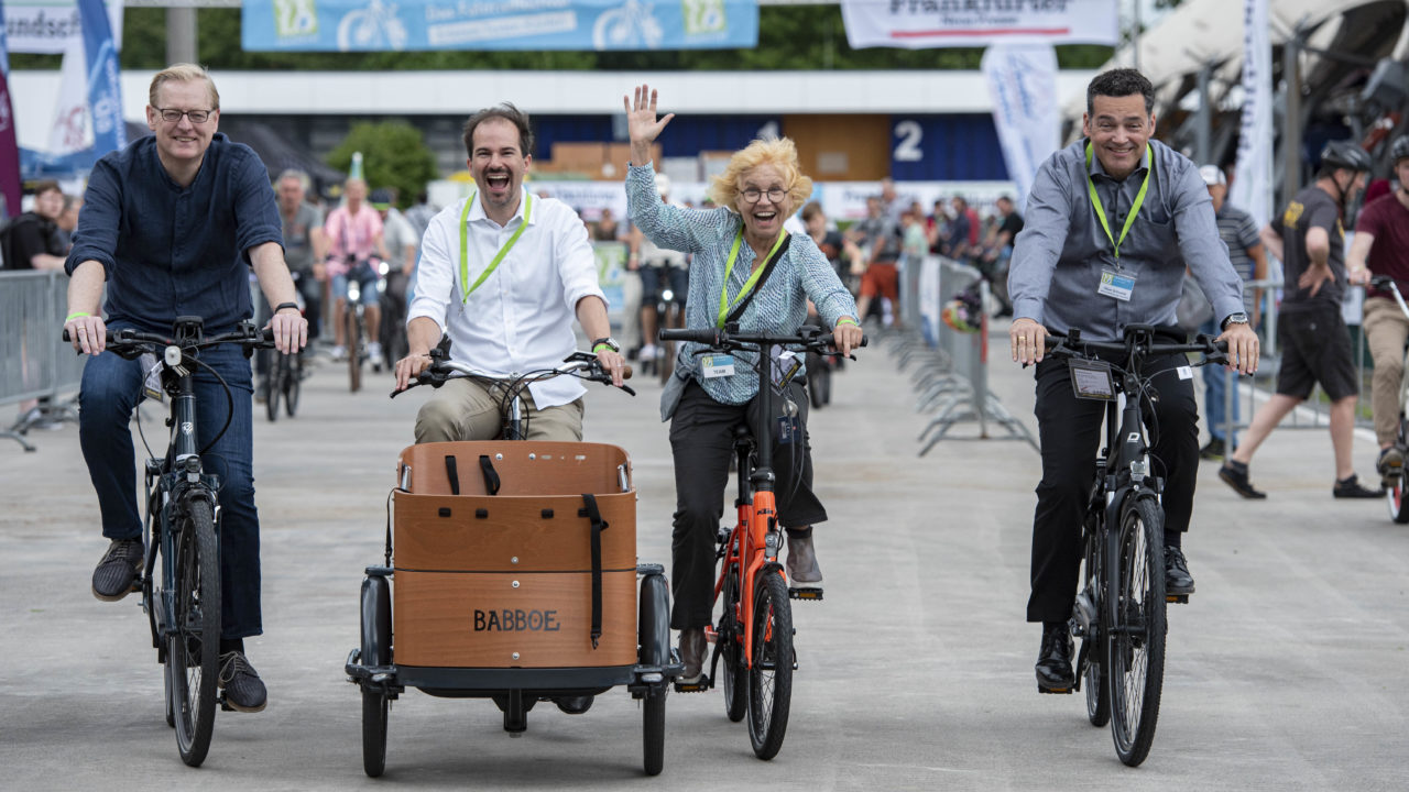 Foto: Vier Fahrradfahrende, die winken