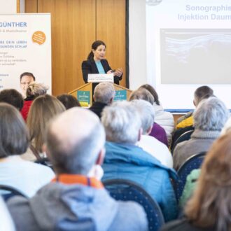 Foto: Eine Frau hält vor vielen Zuhörenden einen Vortrag.